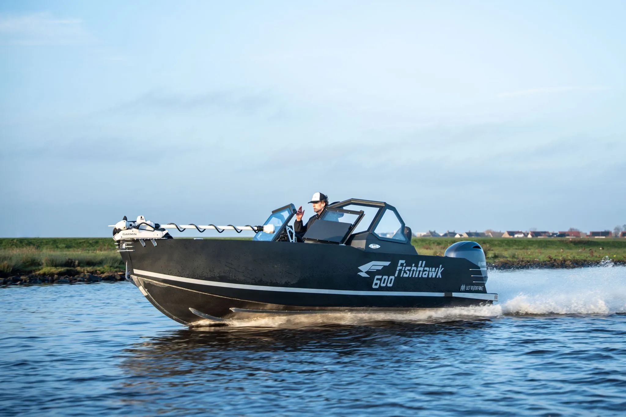 FishHawk 600 vaart langs een rietoever onder een blauwe lucht