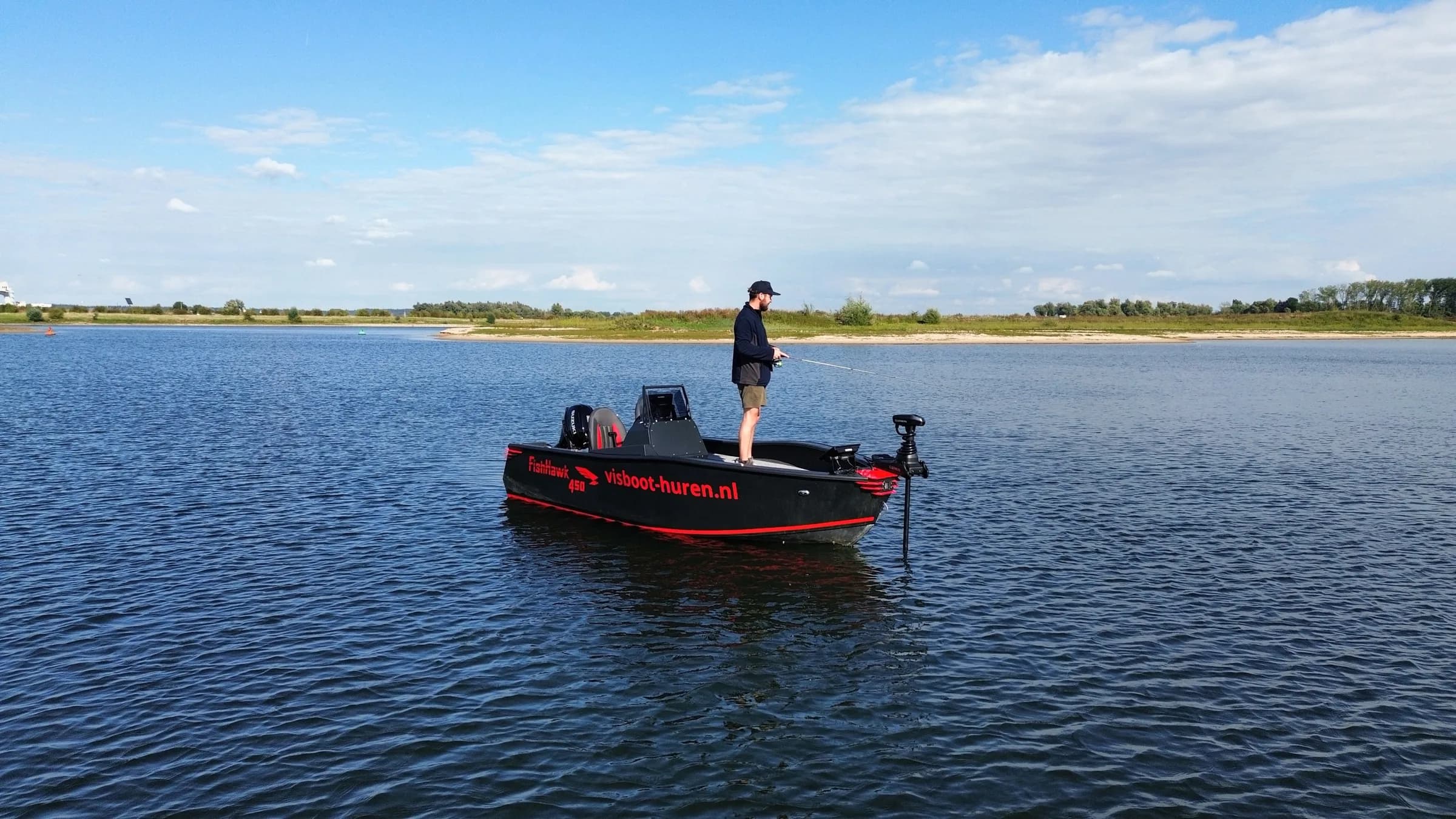 Visser werpt uit vanaf een vaarbewijsvrije FishHawk 450 op een brede rivier